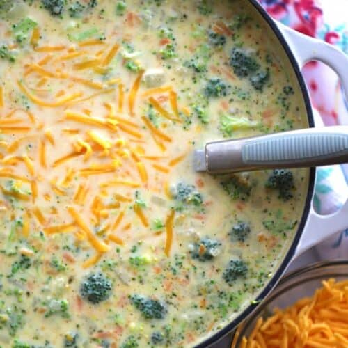 Broccoli Potato Soup in a large dutch oven with a side of shredded cheese.