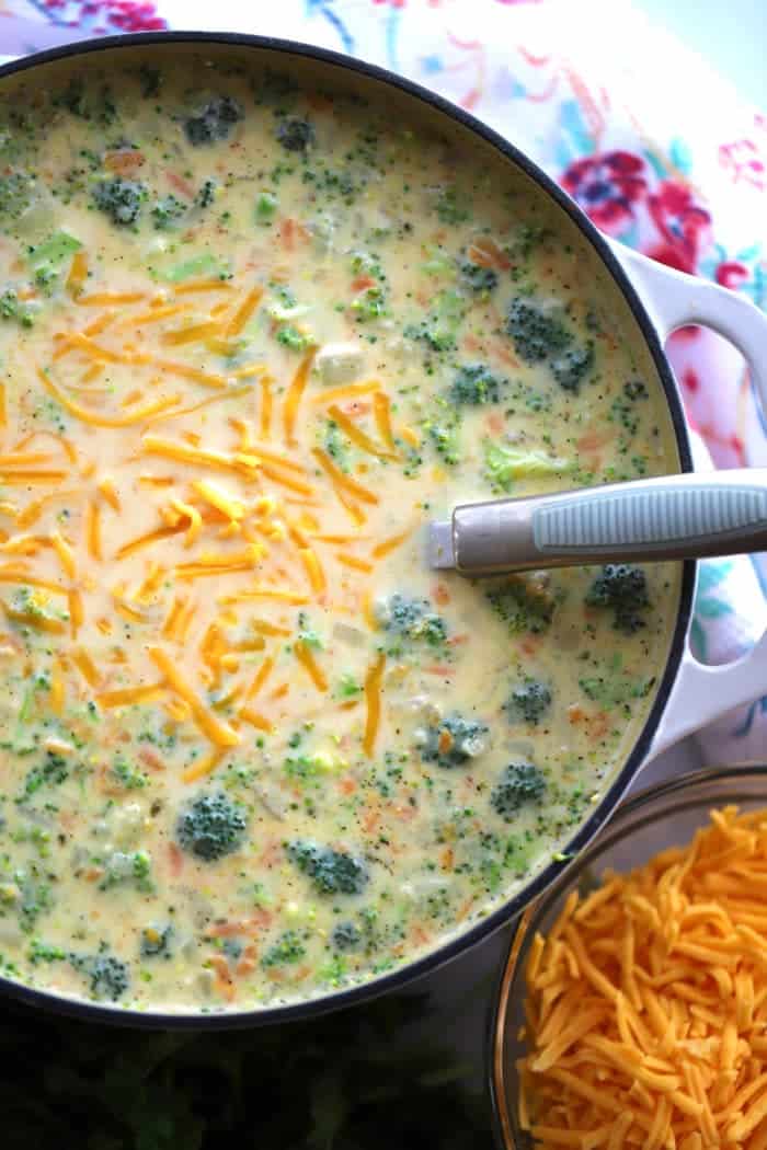 Broccoli Potato Soup in a large dutch oven with a side of shredded cheese.