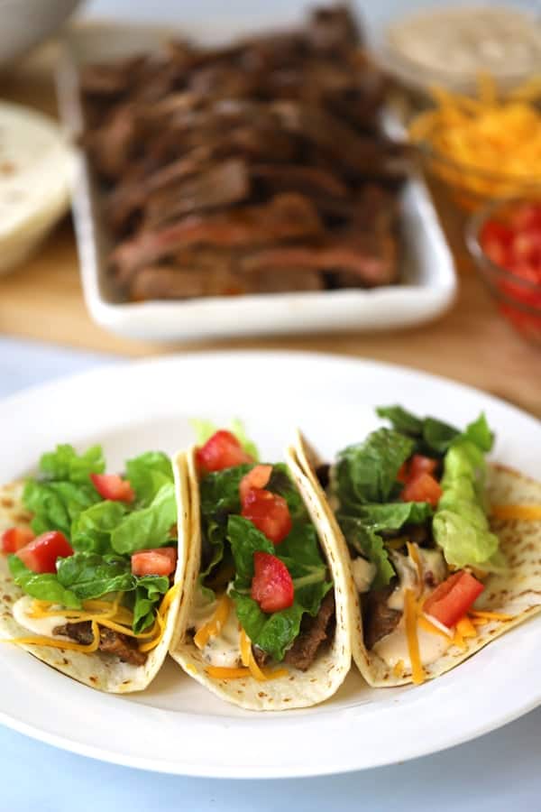 Chipotle Carne Asada on a platter with sliced steak on a dish, carne asada burrito, tacos de cane asada, carne asada recipes, carne asada tacos recipe. 