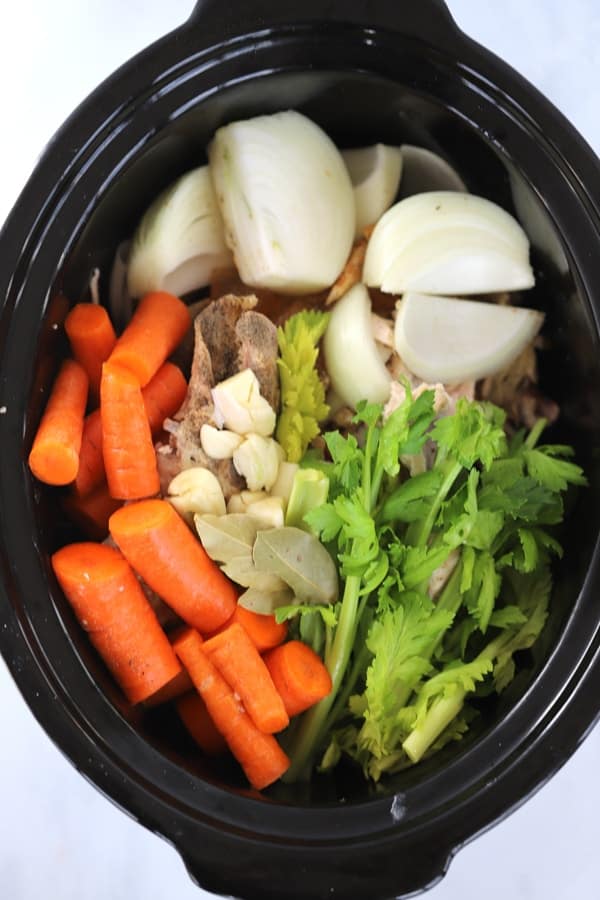 A slow cooker full of ingredients to make this Chicken Stock recipe. how to make chicken stock recipe. 