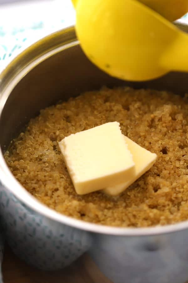 Quinoa in a pot with butter on top and lime juice being squeezed in.