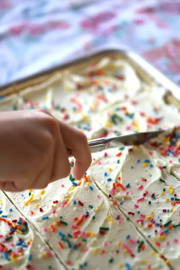 A tray of lemon cookie bars being cut with a knife.