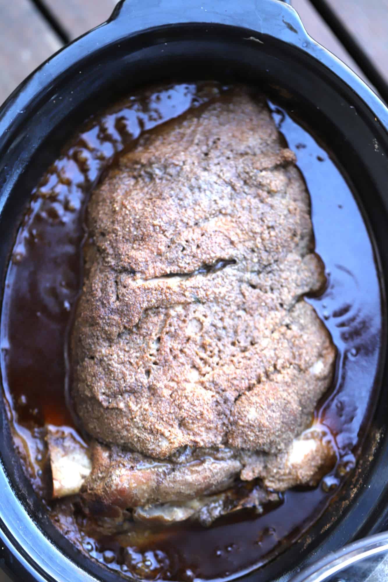 Bone-in pork shoulder in a slow cooker ready to shred into this pulled pork recipe.