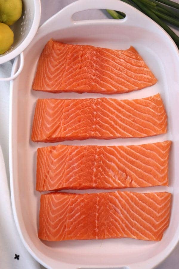 Fresh salmon cut into filets and sitting in a white baking dish ready to make Grilled Teriyaki Salmon. Teriyaki salmon grilled. How to grill teriyaki salmon.