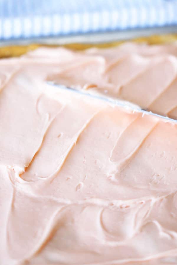 Frosted sugar cookie bars with pink icing before being cut.