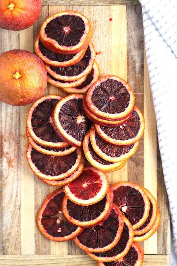 Blood oranges on a a cutting board, ready to make candied citrus.
