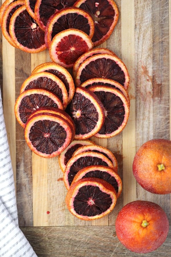 A cutting board with slices of fresh blood oranges.