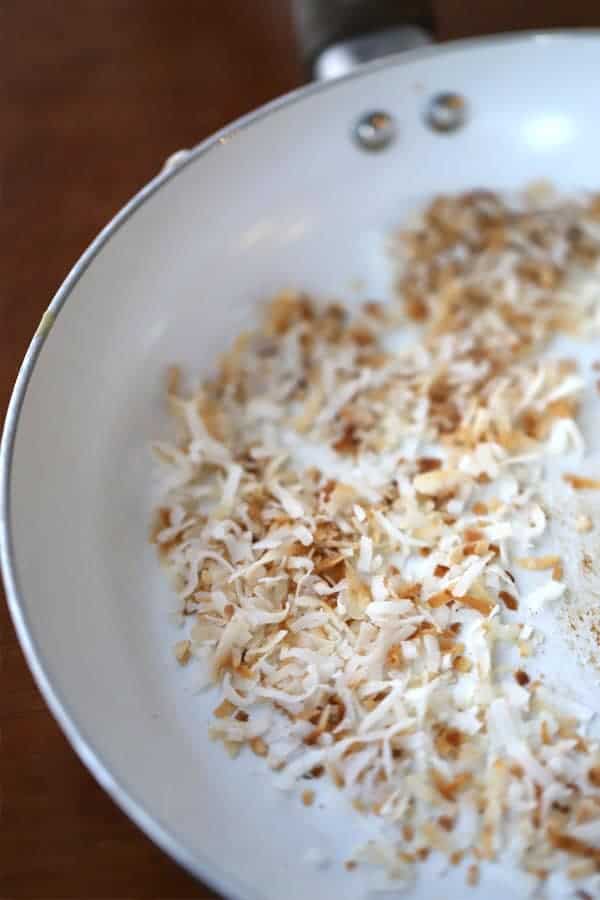 Toasted Coconut in a pan for coconut popcorn, caramel popcorn recipe easy, popcorn toffee. Popcorn coconut. Coconut caramel candy.