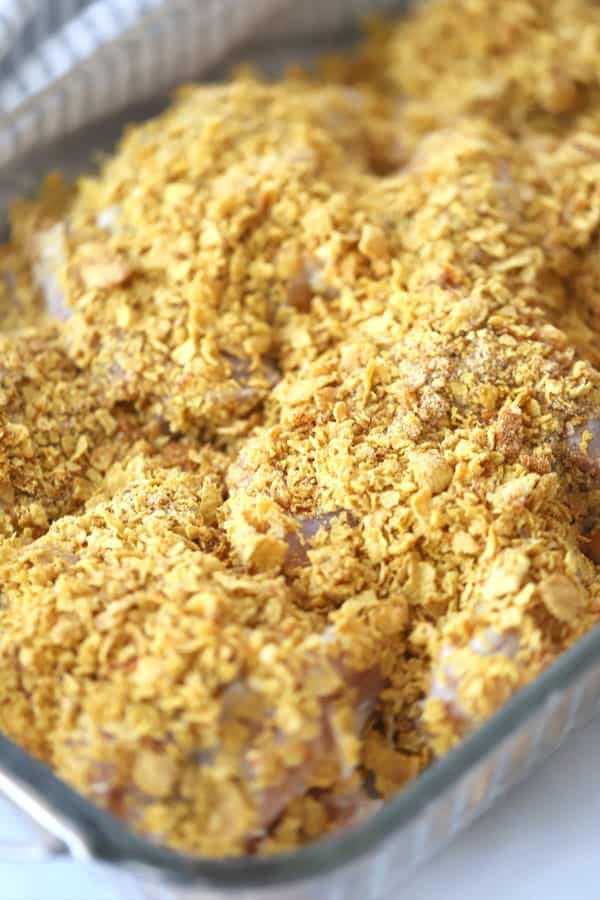 Cornflake crusted chicken in a baking dish, ready to bake