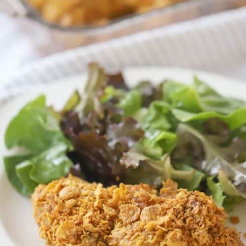 Cornflake fried Chicken on a dinner plate with a green salad, ready to eat.