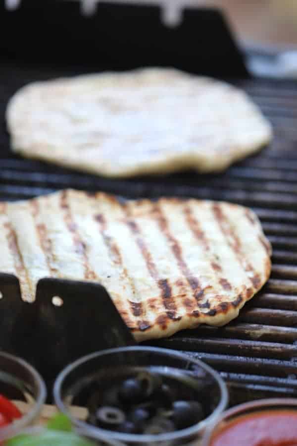 Grilled Pizza dough on a grill with grill marks on the top.