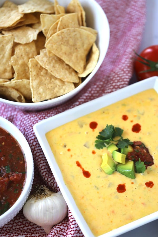 Cheddar queso dip in a bowl served with chips on the side