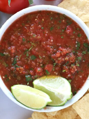 fresh salsa ingredients in a serving bowl with chips and avocado