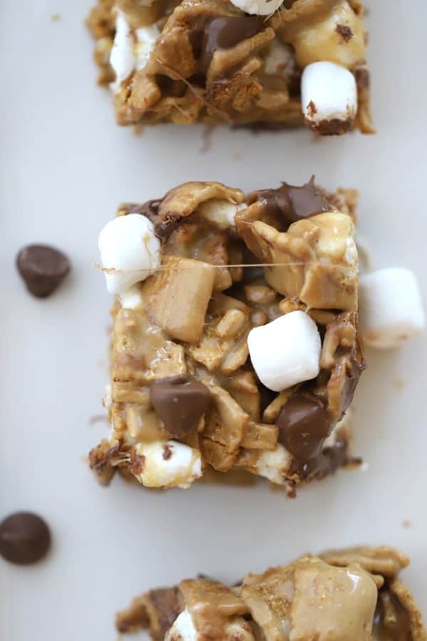S'mores Bars on a tabletop sprinkled with mini marshmallows and chocolate chips.