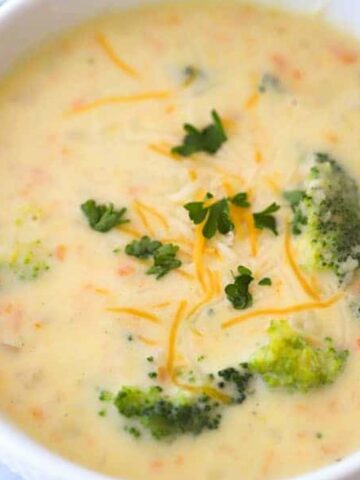 creamy Broccoli Potato cheese soup REcipe in a white bowl with broccoli on top, potato and broccoli soup