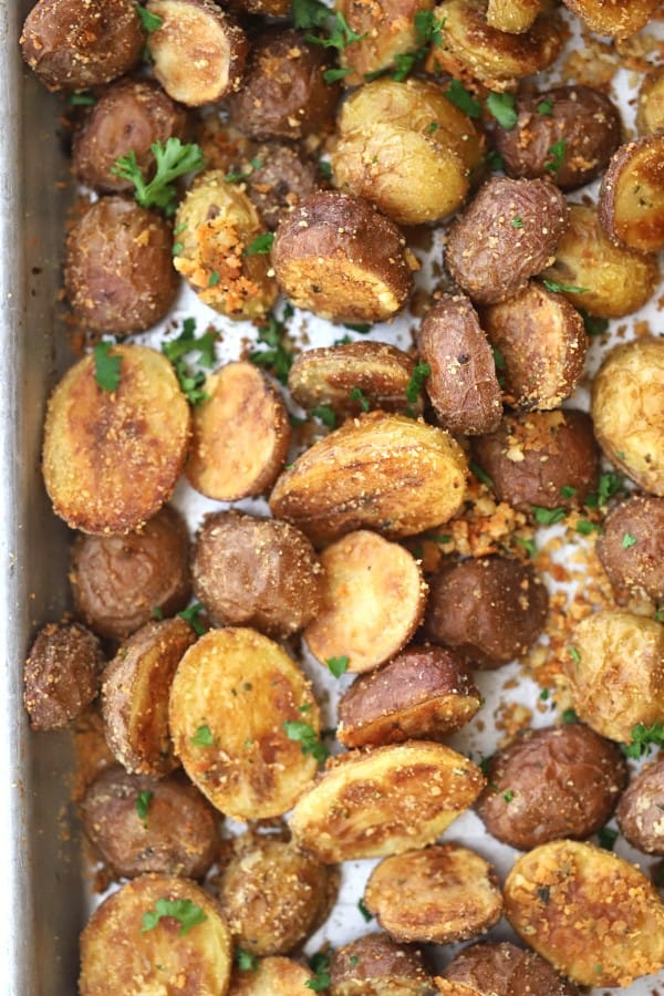 roasted fingerling potatoes on a sheet pan topped with fresh herbs.