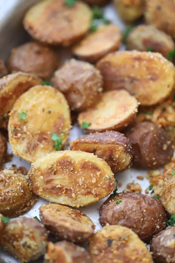 A sheet pan with roasted fingerling potatoes topped with fresh herbs.