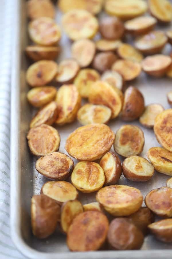 oven roasted fingerling potatoes sliced in half on a baking sheet. rosemary fingerling potatoes. fingerling potato recipes.