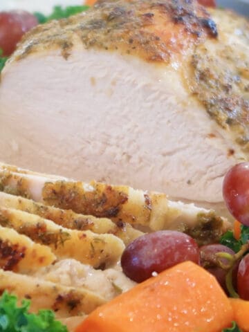 Herb Crusted Turkey breast sliced and on a white platter