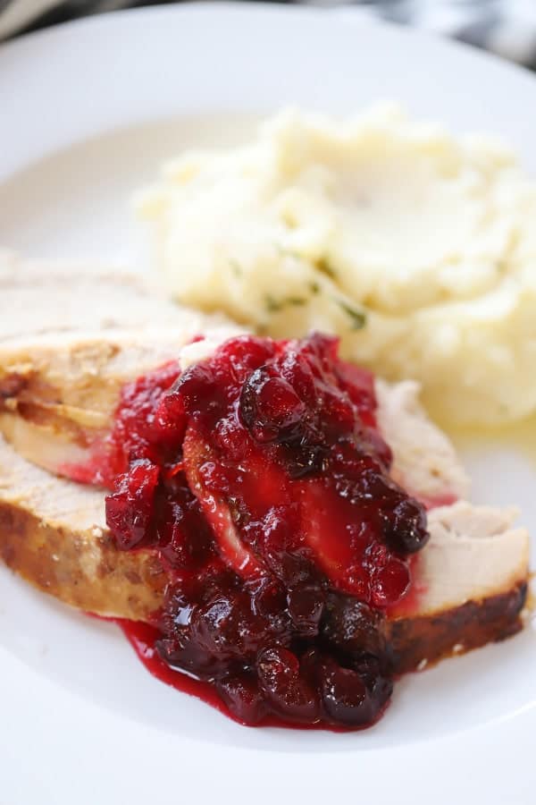 Thanksgiving plate with turkey and sides of cranberry sauce and mashed potatoes.