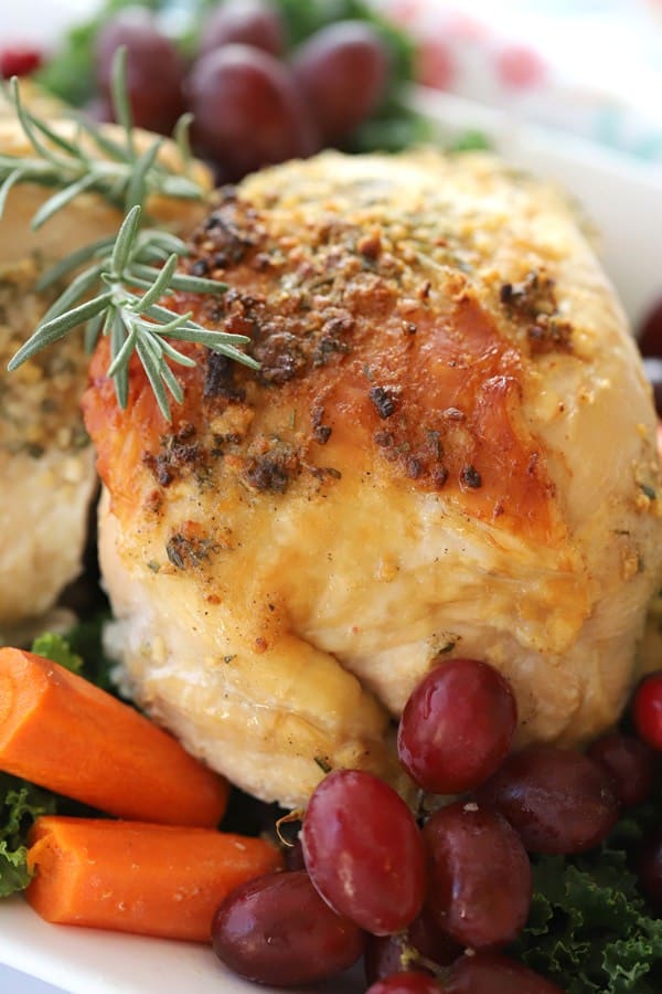 Roasted turkey breast on a platter garnished with rosemary and grapes.