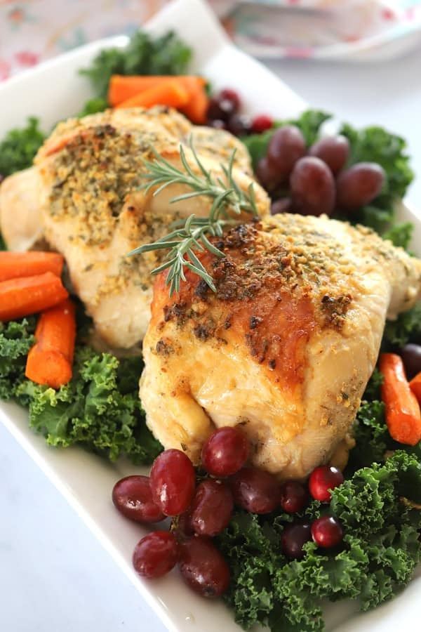 Oven-roasted turkey breast on a serving platter, garnished with rosemary, grapes and roasted carrots.
