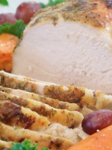 Herb Crusted Turkey breast sliced and on a white platter