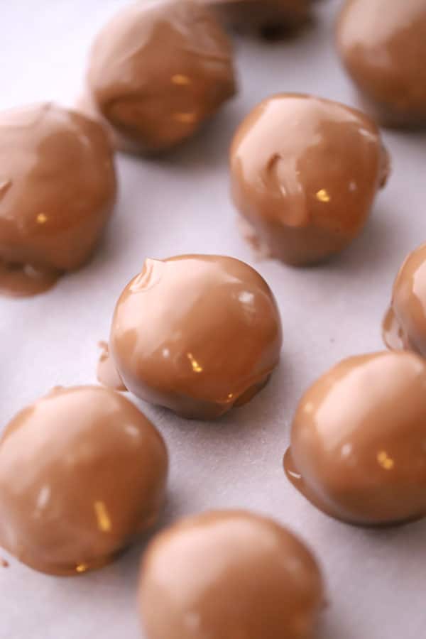 buckeye balls covered with chocolate on a baking sheet, easy buckeye balls, peanut butter balls graham crackers.