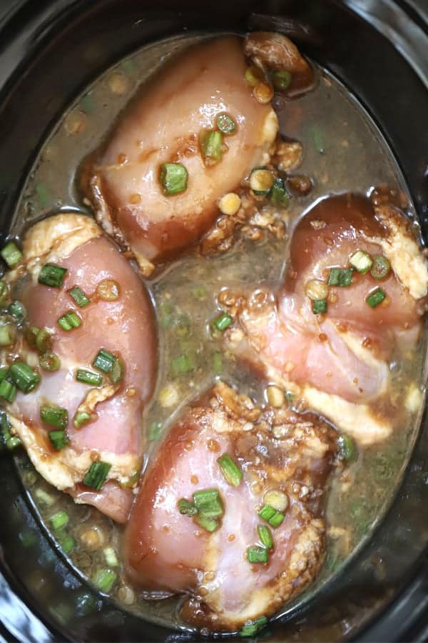 raw chicken thighs in a crockpot with teriyaki sauce
