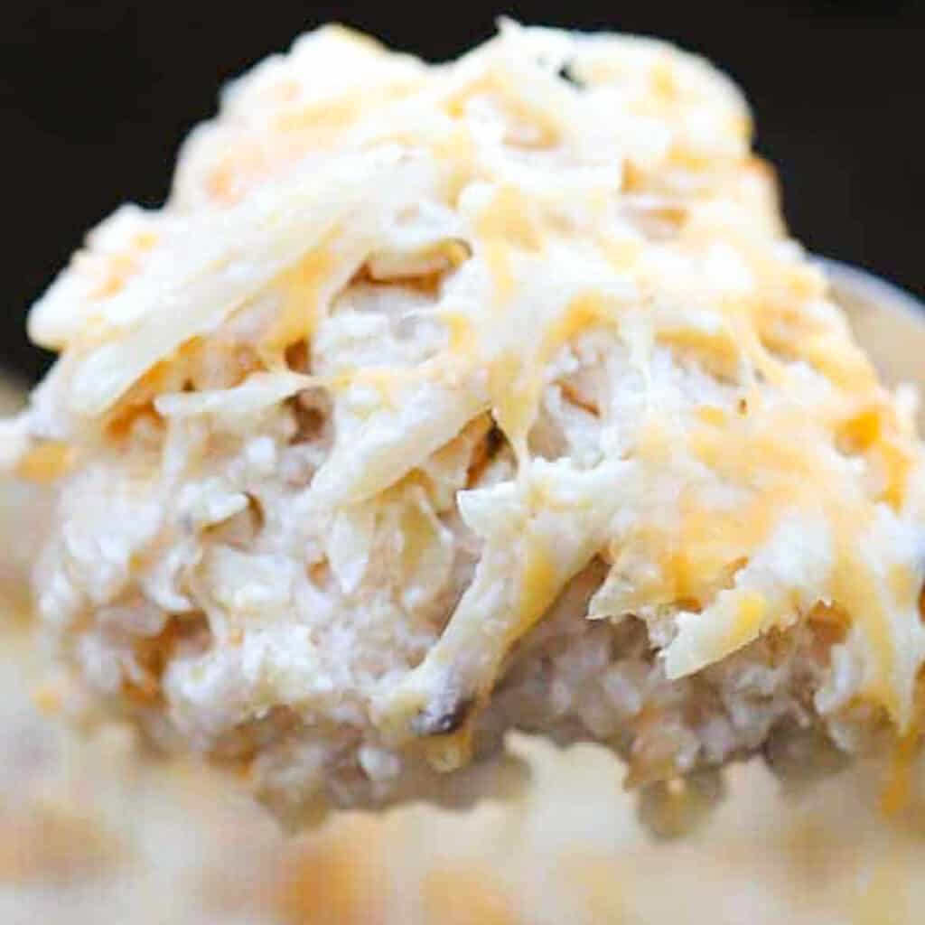 A large spoon full of crockpot cheesy potatoes.