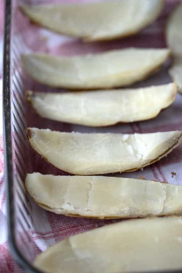 cooked Baked potato skins in a baking dish with the flesh scooped out, ready to be filled.