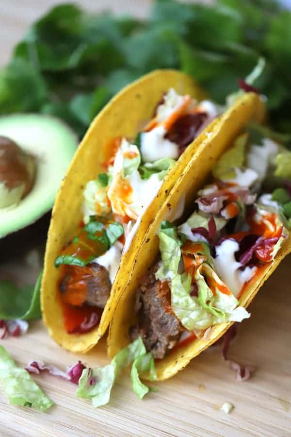 shredded beef tacos recipe in a hard corn tortilla shell on a table.