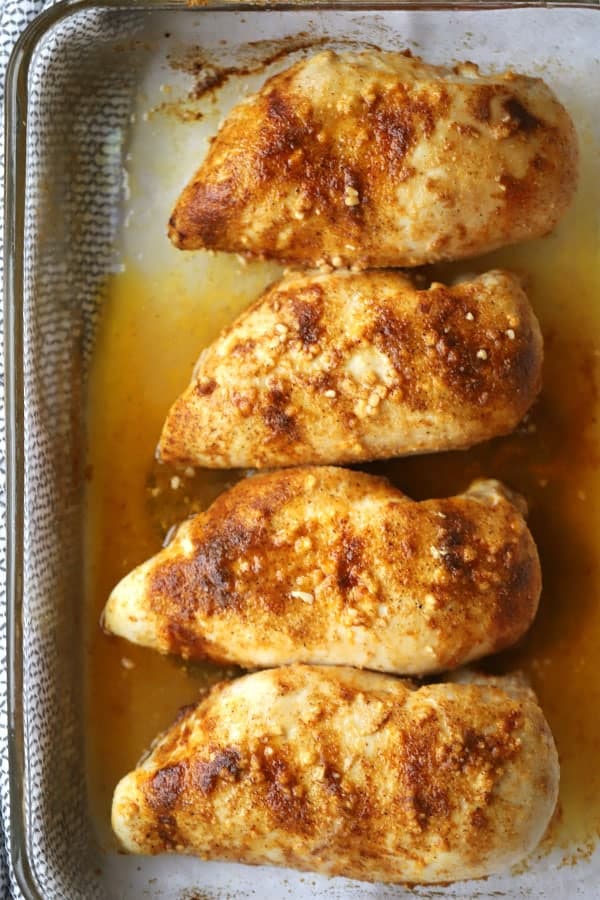 Oven-baked chicken breast on a sheet pan resting in juices.