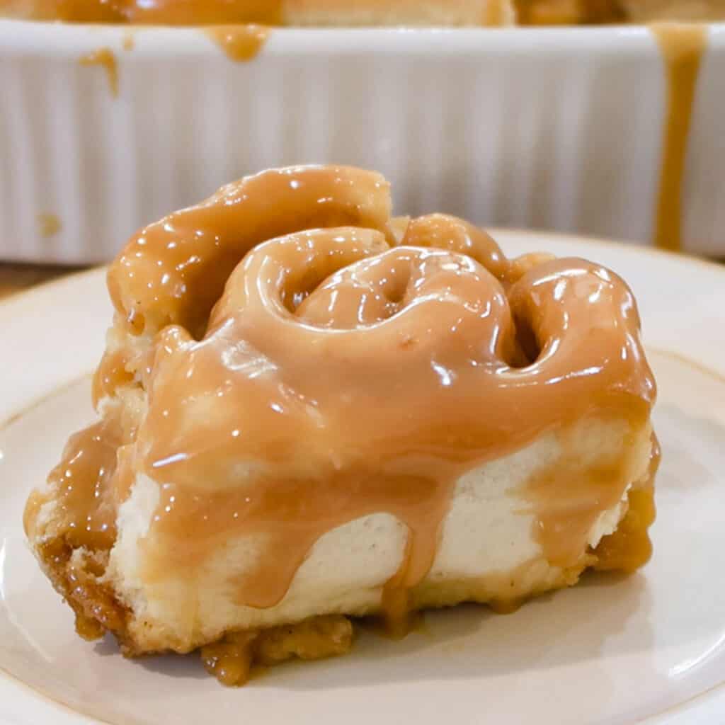 caramel Cinnamon Rolls with caramel Topping on a white plate.