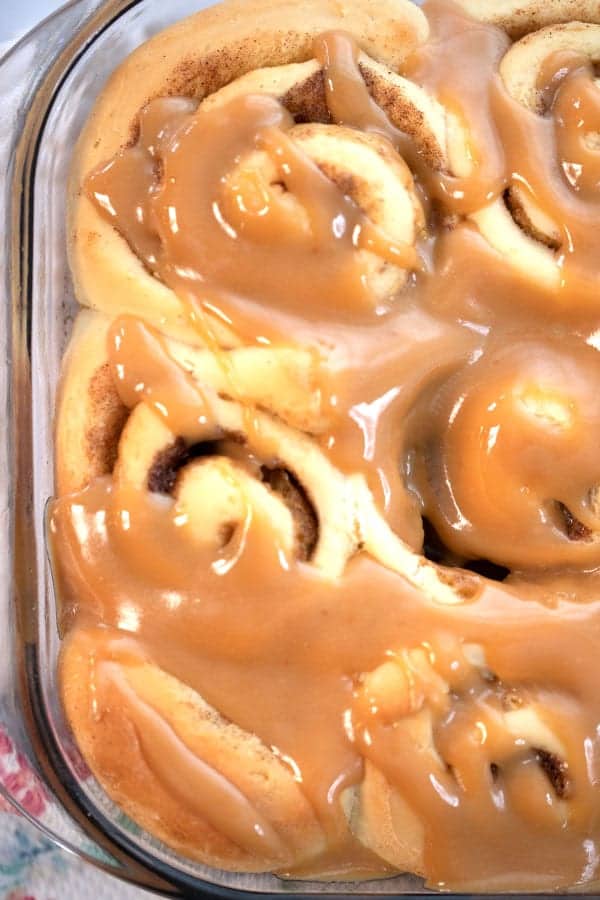 Cinnamon rolls in a glass baking dish covered in caramel sauce.