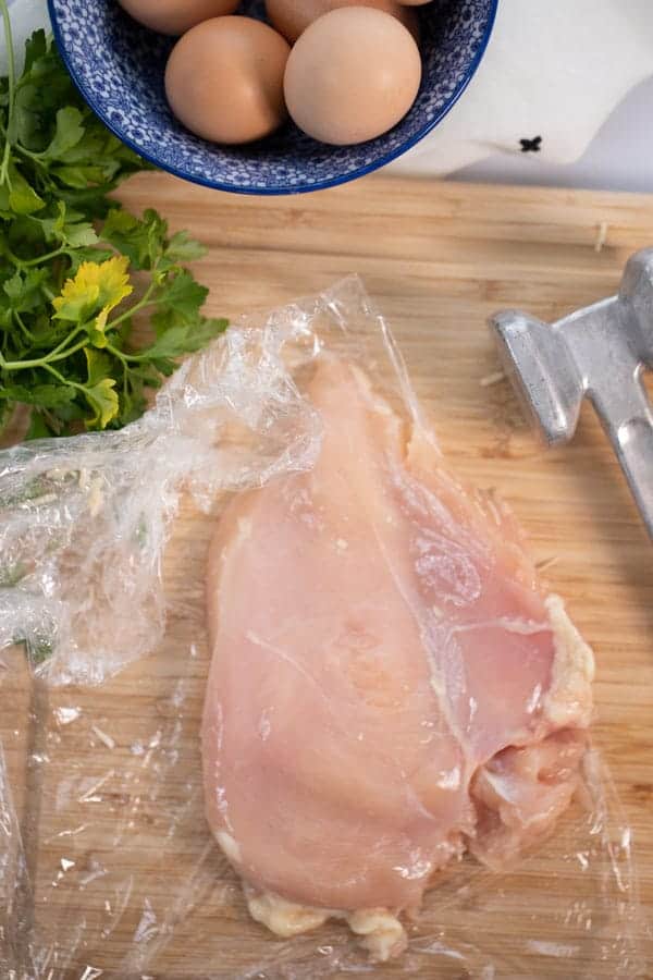 Pounded chicken on a wooden cutting board.