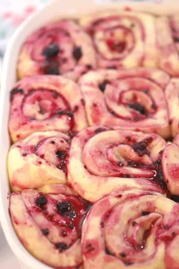 Triple berry sweet cinnamon rolls rising in a baking dish.