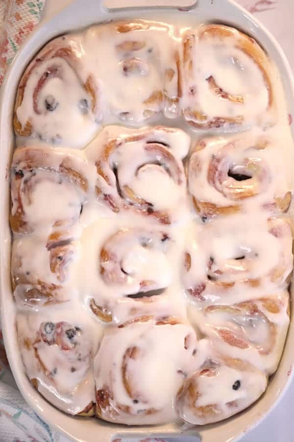Baked cinnamon rolls covered with icing in a baking dish.