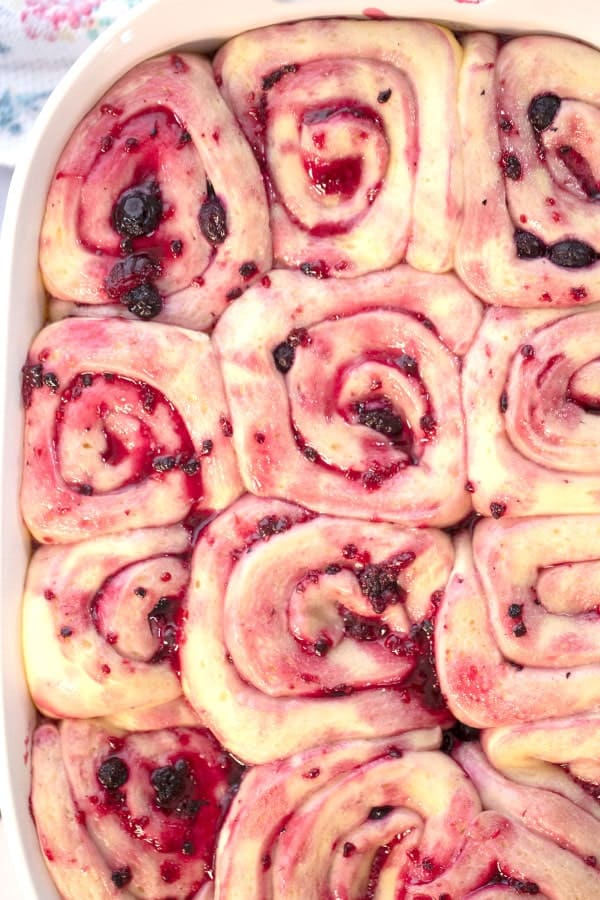 Sweet rolls rising in a white baking dish.