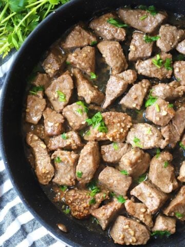 garlic butter steak bites in a pan with parsley