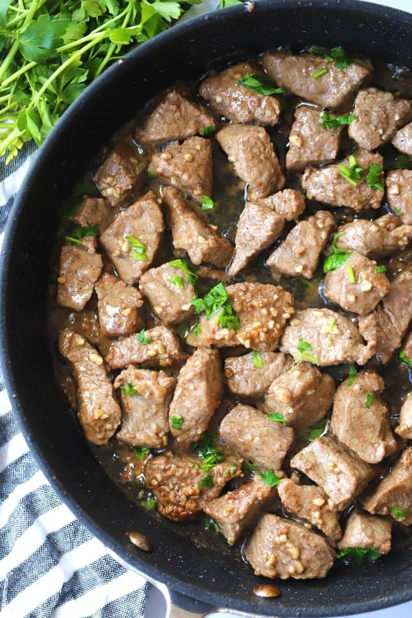 garlic butter steak bites in a pan with parsley