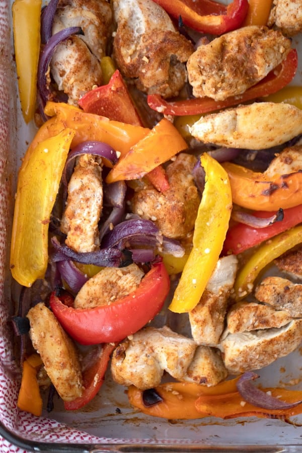 Baked sheet pan chicken fajitas with red, orange, and yellow peppers.