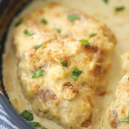 creamy parmesan garlic chicken in a black pan with parmesan sauce