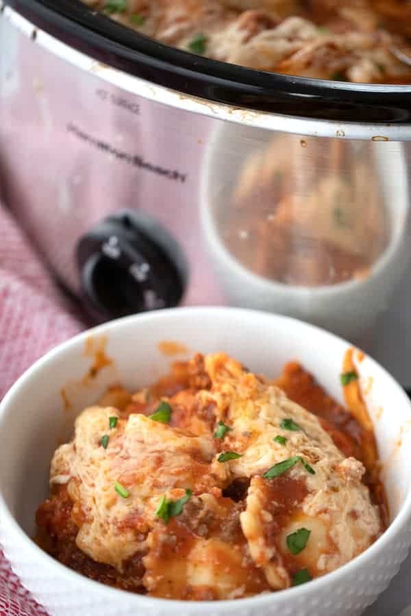 crockpot ravioli lasagna  in a white bowl, lazy crockpot pot lasagna recipe in a serving bowl. 