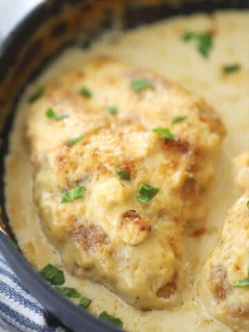 creamy parmesan garlic chicken in a black pan with parmesan sauce