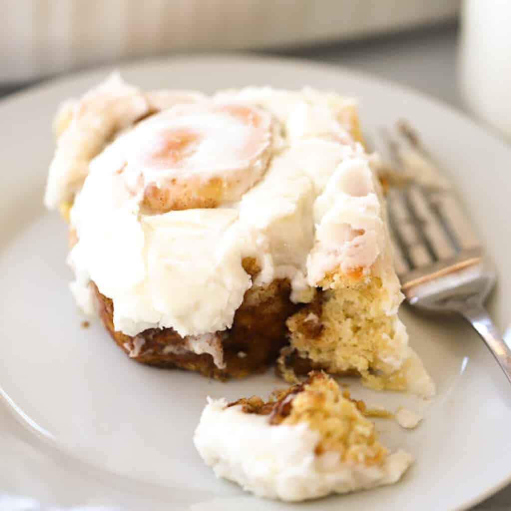 einkorn cinnamon roll on a white plate with frosting, one of my favorite cinnamon roll variations.