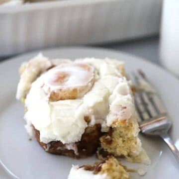 einkorn cinnamon roll on a white plate with frosting