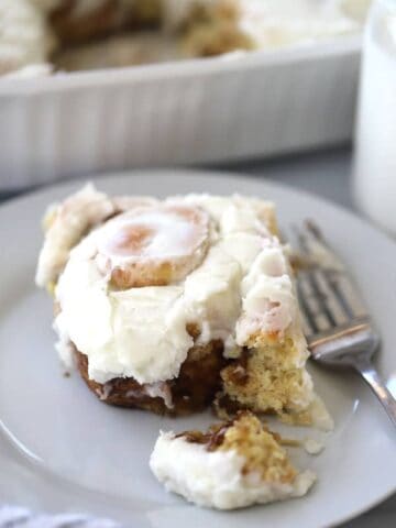 einkorn cinnamon roll on a white plate with frosting