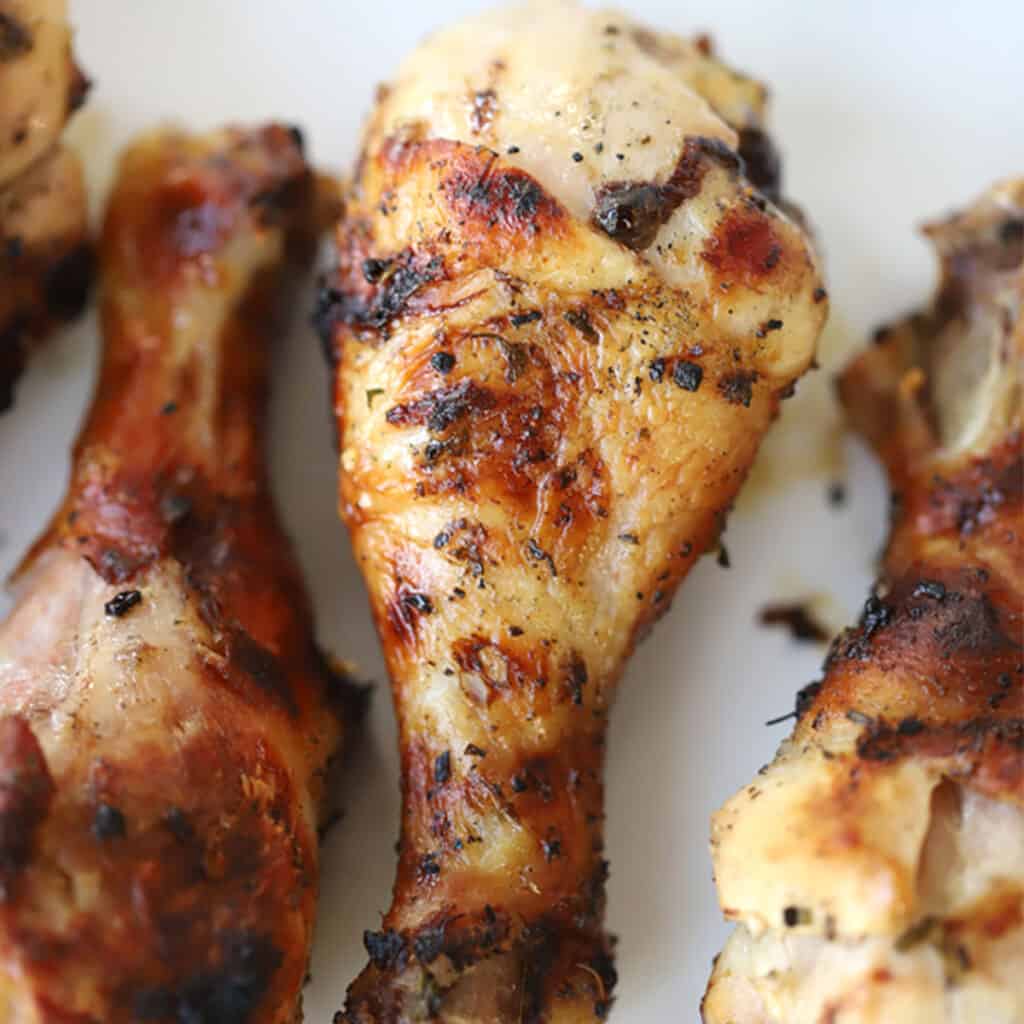 Mediterranean grilled chicken on a white plate, chicken drumstick marinade for bbq, mediterranean chicken legs on the grill.