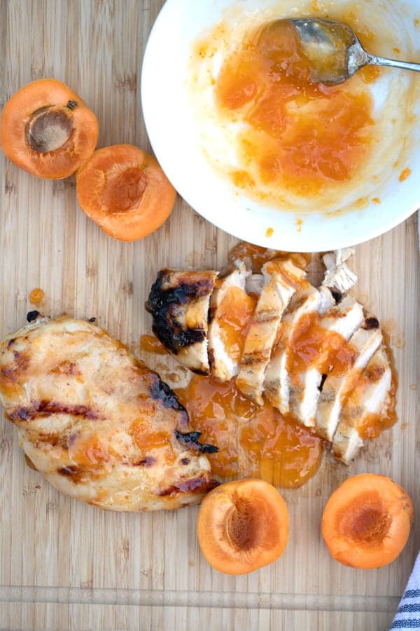 apricot chicken glaze with chicken breast on a wood cutting board with fresh apricots